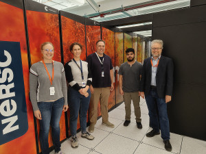 Five people in front of Perlmutter supercomputer 