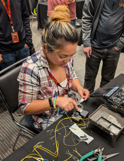 A person bending over and soldering cable