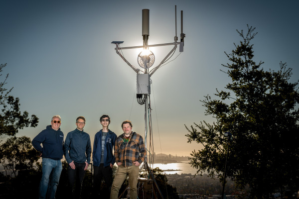 Four people staring into the sun with a wireless tower behind them