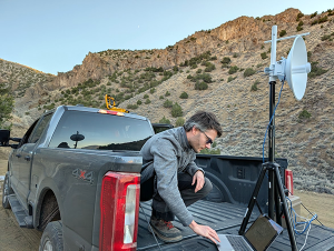 Man in truckbed studying laptop