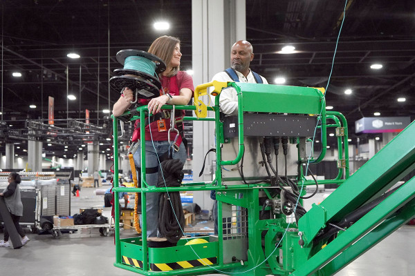 Woman in a cherry picker hlding a cable spool